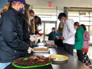 Students gathered around a table with baked goods at the Green Team fundraiser.