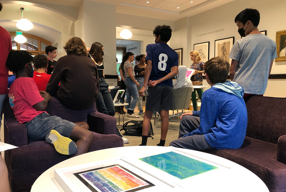 Teacher of Art Sarah Mango talks with students at the art exhibit of their prints in the Cummings Room.