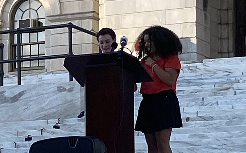 Two Hamilton School students stand at a podium on the steps of the Rhode Island State House while speaking at an event for Dyslexia Awareness Month.
