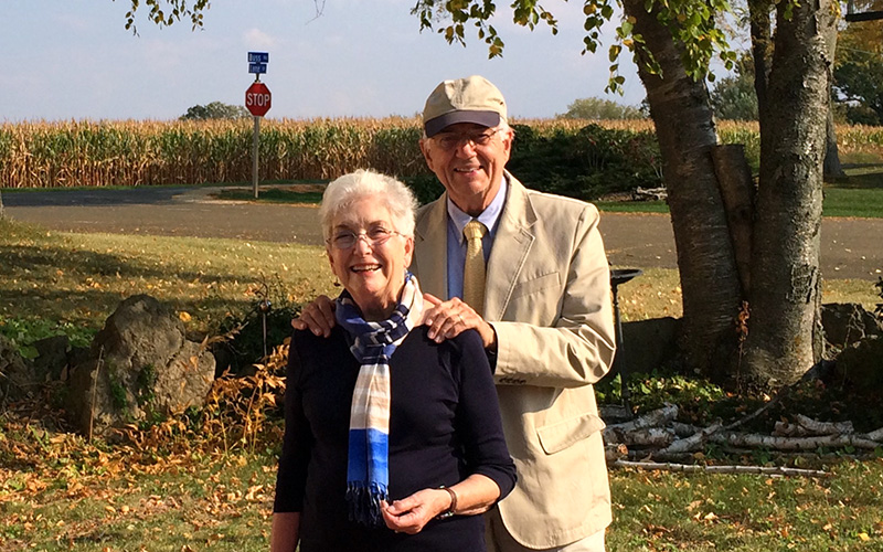 Guy and Marilyn Martin stand together outside and smile at the camera.