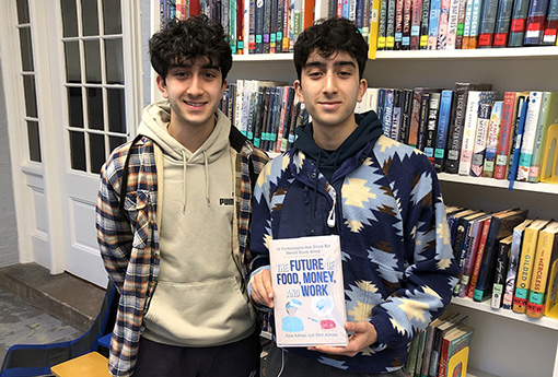 Alex and Eliot Advani pose in a library while holding their book.