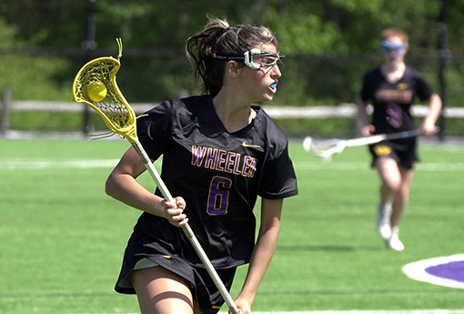 Sadie M. '24 carries the ball with her lacrosse stick during a game.}