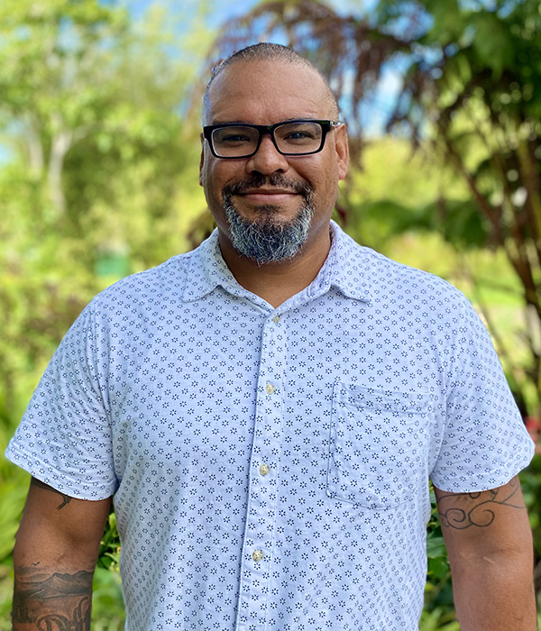 A photo of Upper School Dean of Students Abraham Henderson standing outside and smiling at the camera.