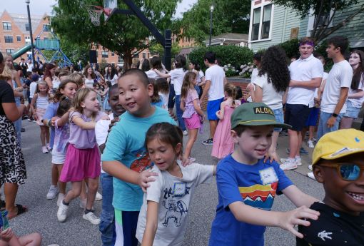 Children dancing in a conga line outside the Wheeler School courtyard.