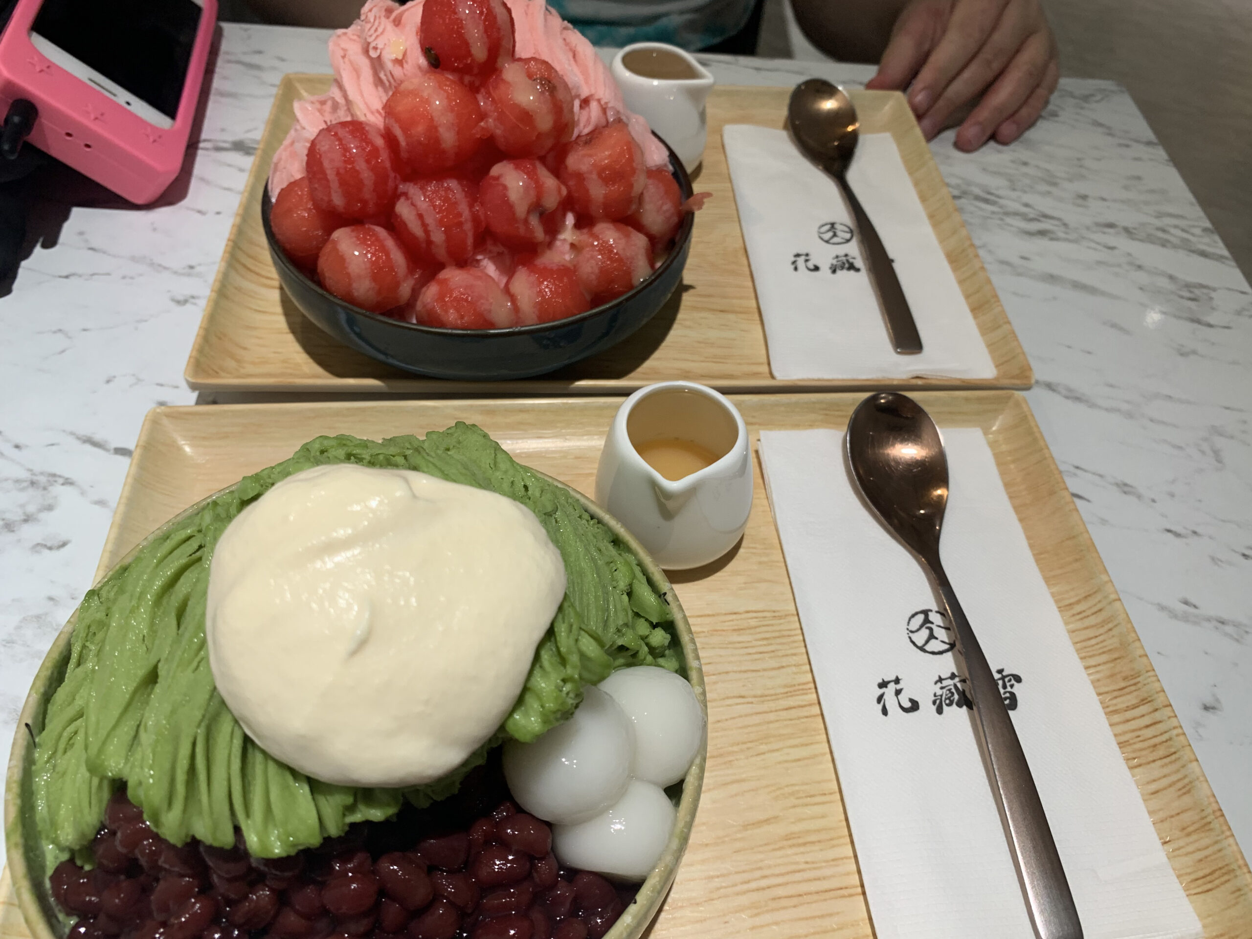 A photo taken by Caroline showing two plates of shaved ice dessert with Wheeler alum Naomi Blank's hand in the far right corner at the Shilin Night Market.