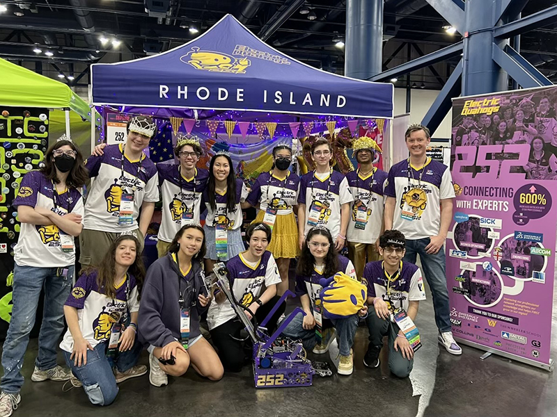 Group photo of Wheeler's FIRST Tech Challenge (FTC) Robotics teams, Electric Quahogs, in front of their booth at the FTC World Championship in Houston, Texas.