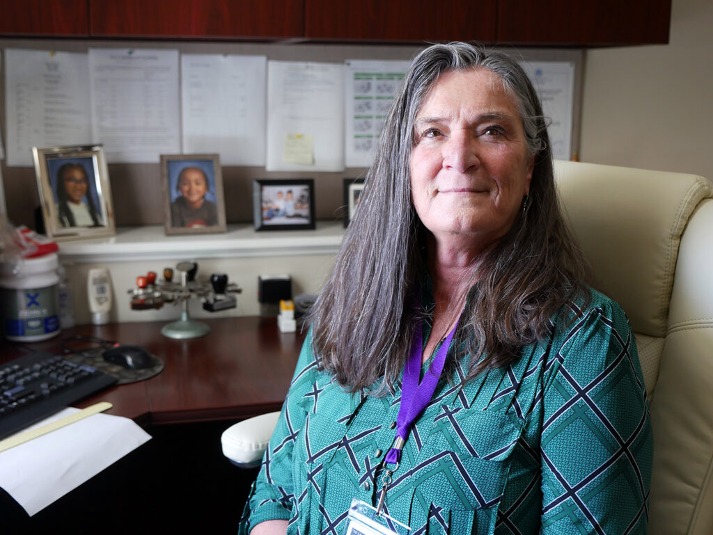 A photo of Cindy Olbrych sitting at her desk and smiling at the camera.