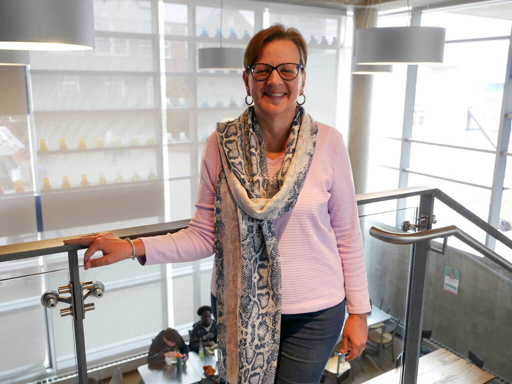 A photo of Judy Poirier standing in the Nulman Lewis Student Center and smiling towards the camera.
